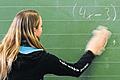 Fürs Leben lernen: Eine Schülerin steht vor einer Rechenaufgabe an der Schultafel im Klassenzimmer.