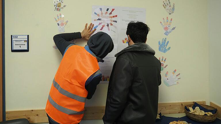 Das Bild hängt schief im Ankerzentrum: Zwei junge Deutsch-Schüler rücken es wieder zurecht. Das Bild hängt schief im Ankerzentrum: Zwei junge Deutsch-Schüler rücken es wieder zurecht.