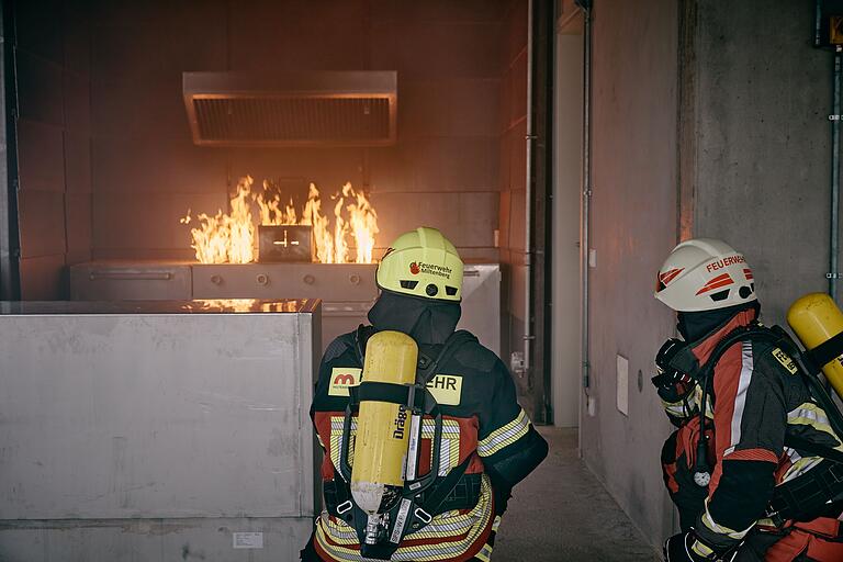 Feuerwehrleute simulieren das Löschen eines brennenden Imbiss-Grills.