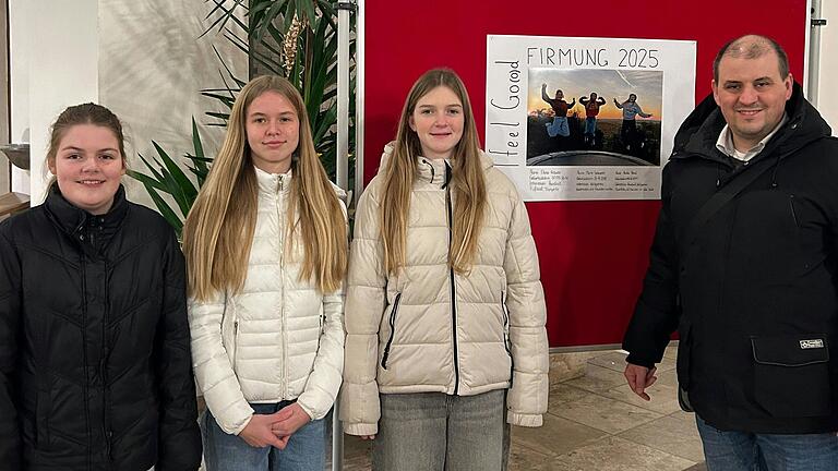 Die Firmlinge (von links) Elena Krause, Marie Scheuerer und Annika Hönnl stehen mit Pastoralreferent und Koordinator Florian Meier vor dem Symbolbild 'Feel Go(o)d' der Firmung 2025.