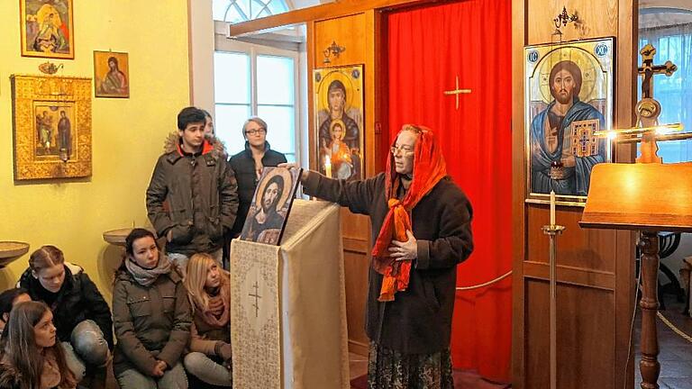 Sofia Khorobrykh zeigte bei der Interreligiösen Shuttle-Tour in Würzburg die zahlreichen Ikonen im Gebetsraum der russisch-orthodoxen Gemeinde Würzburg. Hinter dem roten Vorhang verbirgt sich der Altar, der heiligste Ort im Gebetsraum.