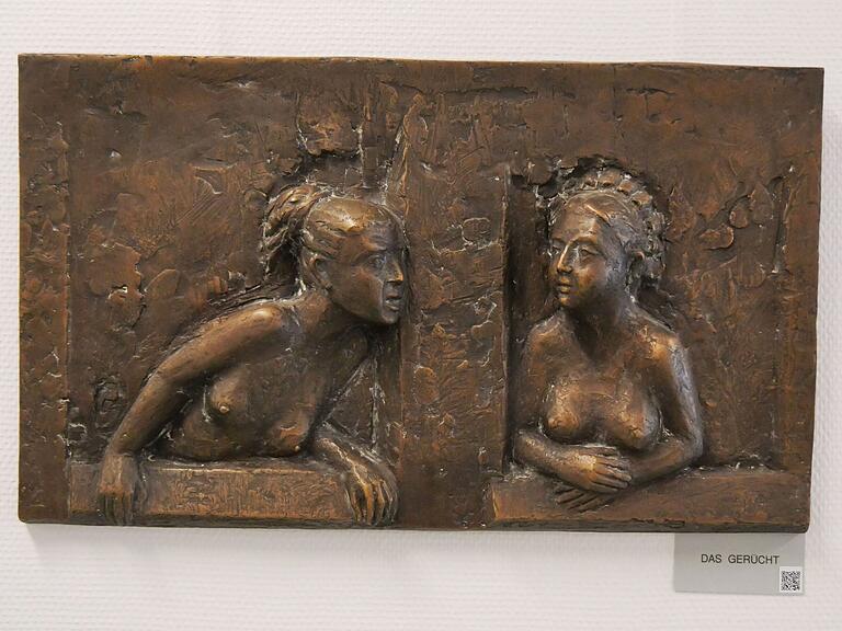 Aus Bronze ist dieses Kunstwerk namens 'Das Gerücht'. Zwei Frauen unterhalten sich am Fenster. 'Hast du es schon gehört?'