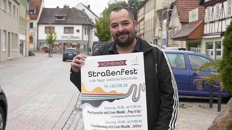 Werbering-Vorsitzender Rene Tierno mit einem Plakat des 1. Hofheimer Straßenfests, das am Wochenende in der Stadt gefeiert wird.