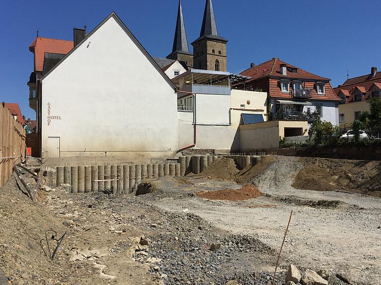 Tief ins Erdreich hineinragende Betonsäulen sichern die künftige Tiefgarage. Während sie an der Nordseite des Baugrundstücks schon sichtbar sind, sind sie an den übrigen Bereichen (zum Beispiel vorne links) noch bündig mit dem Erdreich und kaum zu erkennen.