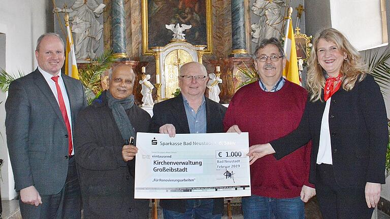 Einen Scheck über 1000 Euro überreichte Sparkassen-Gebietsdirektor Peter Lindemann (links) an Pfarrer Benjamin Pereira, Reinhard Kleinhenz von der Kirchenverwaltung und  Kirchenpfleger Lothar Radina. Mit auf dem Bild Ulrike Russek Privatkundenberaterin der Sparkasse Bad Königshofen. Im Hintergrund der historische Hochaltar aus der unter Julius Echter erbauten Kirche. Hier soll eine Tauf- und Anbetungskapelle entstehen.