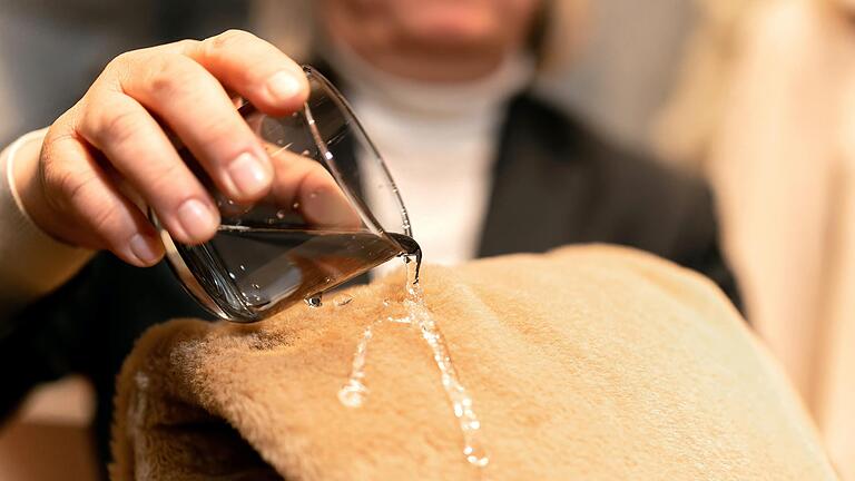 Schmutz- und wasserabweisend ist ein Alpaka-Mantel. Bernd Heilmann führt vor, wie das Wasser abperlt.