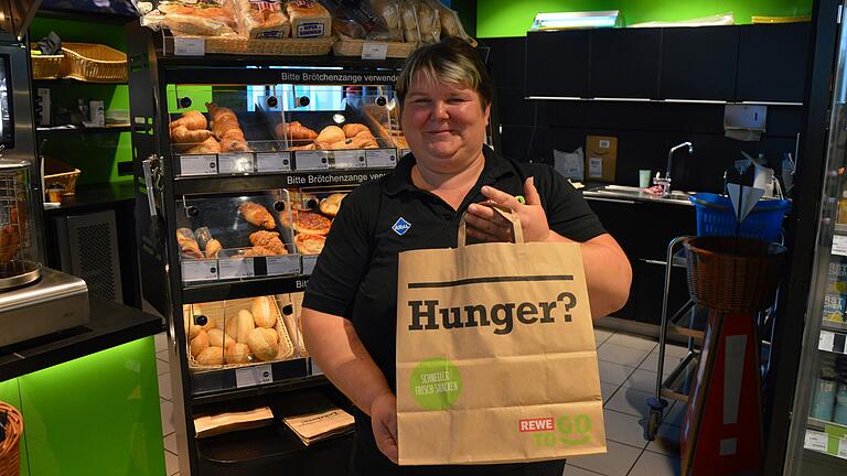 Andrea Hüßner, Mitarbeiterin bei der Aral Tankstelle in Schwarzach, mit einer Überraschungstüte für Too Good To Go-Kunden, die mit Backwaren, Snacks und Artikeln aus dem Shop gefüllt ist. Täglich verkaufen sie und ihre Kollegen fünf bis sieben solcher Tüten. Andrea Hüßner, Mitarbeiterin bei der Aral Tankstelle in Schwarzach, mit einer Überraschungstüte für Too Good To Go-Kunden, die mit Backwaren, Snacks und Artikeln aus dem Shop gefüllt ist. Täglich verkaufen sie und ihre Kollegen fünf bis sieben solcher Tüten.