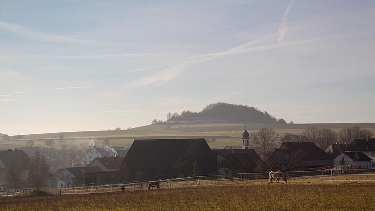 Blick auf Hetzlos im Jahr 2014 mit der markanten Kirchturmspitze und Blick auf den Büchelberg       -  Blick auf Hetzlos im Jahr 2014 mit der markanten Kirchturmspitze und Blick auf den Büchelberg