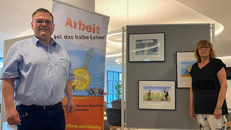 Im Foyer des Schweinfurter Landratsamts sind ab Donnerstag 60 Karikaturen zum Thema 'Arbeit ist das halbe Leben?' zu sehen. Nach Schweinfurt geholt haben die Ausstellung Diakon Peter Hartlaub und Kathi Petersen von Verdi (von links).