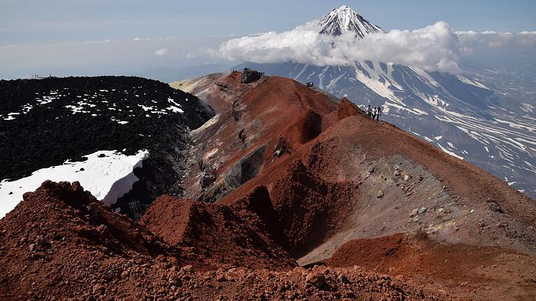 Auf dem Vulkan Avacinskij gibt es schwarze und rote Lava. Im Hintergrund der 3458 Meter hohe Vulkan Korjakskij mit den typischen Ufo-Wolken.&nbsp;