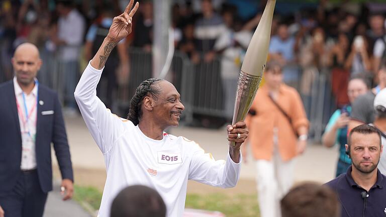 Paris 2024 - Fackellauf       -  Rap-Star Snoop Dogg trägt die olympische Flamme.