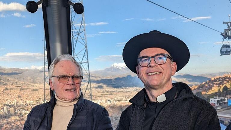 Josef Schnackig und Bischof Dr. Franz Jung sitzen beim Besuch der Würzburger Delegation in der Seilbahn über La Paz.