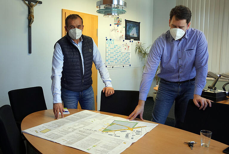 Bürgermeister Alois Fischer (links) und der Zahnmediziner und Oralchirurg Dr. Etienne Loho begutachten den Bebauungsplan des Gewerbegebiets Windmühle in Unterpleichfeld.