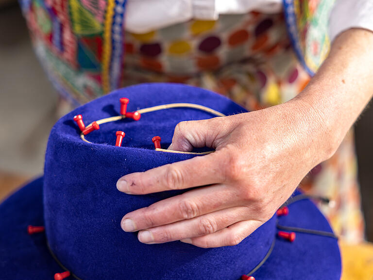 Der Filz wird mit Pins auf der Holzform fixiert, mit einem Modistendraht wird der Kopf des Hutes befestigt. Der Filz wird mit Pins auf der Holzform fixiert, mit einem Modistendraht wird der Kopf des Hutes befestigt.