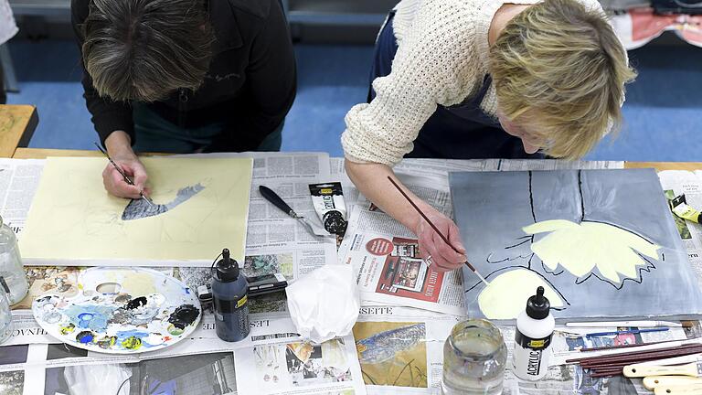 Malen lernen an sechs Abenden: Paula Stang (links) und Petra Wagner-Schad sind beim Acrylmalkurs der Volkshochschule in Kitzingen über ihre Kunstwerke gebeugt.