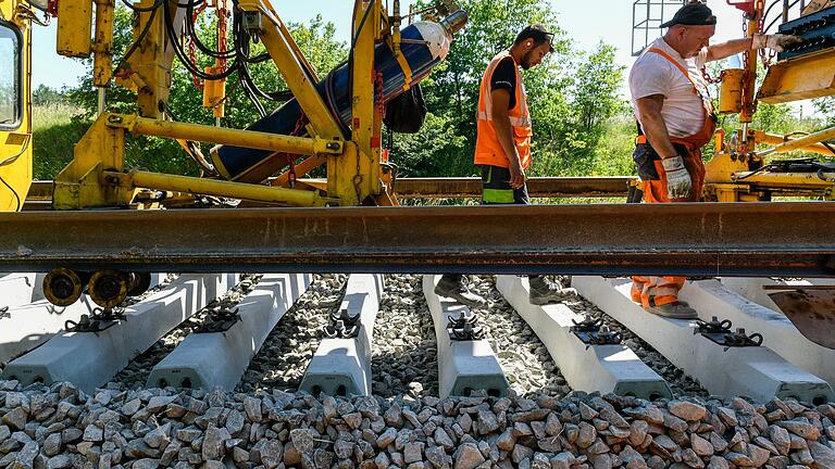 Eine riesige Maschine, ein sogenannter Gleisumbauzug, tauscht alte gegen neue Schwellen und Schienen aus, die Arbeiter steuern und kontrollieren den Fortgang.