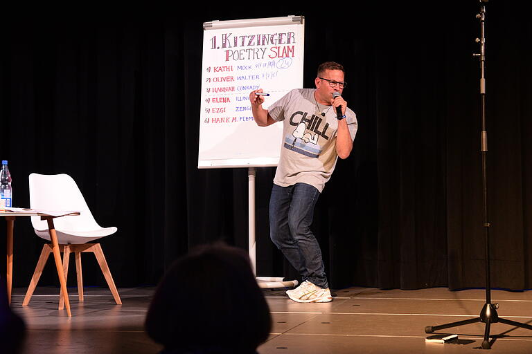 Moderator Manfred Manger nimmt die Wertungen der Publikum-Jury beim 1. Kitzinger Poetry Slam entgegen. Moderator Manfred Manger nimmt die Wertungen der Publikum-Jury beim 1. Kitzinger Poetry Slam entgegen.