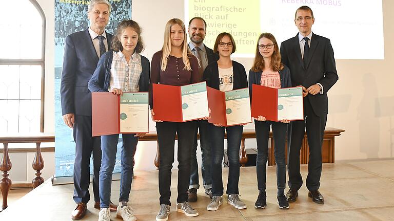 Beim Geschichtswettbewerb des Bundespräsidenten: Die Preisträgerinnen aus Münnerstadt (Hanna Lommel, Matilda Spieß, Selma Gaiser, Rebekka Möbus) und ihr Tutor Daniel Karch. Links im Bild der Ministerialdirektor des Bayerischen Staatsministeriums für Unterricht und Kultus Herbert Püls zu sehen, rechts . Thomas Paulsen, Vorstandsmitglied der Körber-Stiftung, die beiden zeichneten die Mädchen mit den Urkunden aus.