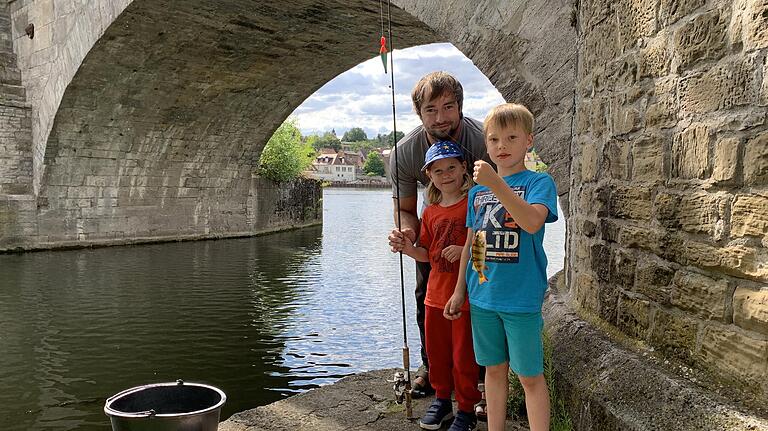 Familienbande: Ceven Klatt mit seinen Kindern Ronja (5) und Erik (6), die ebenfalls schon angeln, am Fuß der Alten Mainbrücke in Kitzingen-Etwashausen. Ein kleiner Barsch zappelt an der Schnur. Familienbande: Ceven Klatt mit seinen Kindern Ronja (5) und Erik (6), die ebenfalls schon angeln, am Fuß der Alten Mainbrücke in Kitzingen-Etwashausen. Ein kleiner Barsch zappelt an der Schnur.