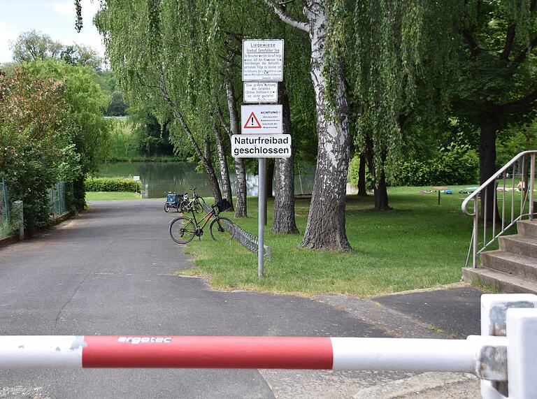 Offiziell ist das Badesee Sennfeld, ein Naturfreibad, noch geschlossen, wie dieses Schild aussagt. Tatsächlich liegen einige Besucher auf der Wiese.