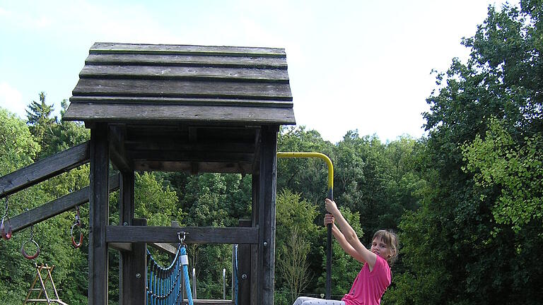 Zwischen Weinbergen und Wald liegt auf der Straße nach Birklingen der Iphöfer Spielplatz Ringsbühl. Das sehr weitläufige Gelände lockt die Kinder mit einem Kletterstein und einer Seilbahn. Die Erwachsenen finden in der wenige Gehminuten entfernten Kneipp-Anlage Erfrischung.
Maria (8 Jahre) auf dem Klettergerüst.