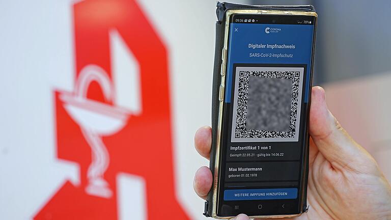 Der digitale Impfnachweis ist vor dem Apotheken-Logo auf einem Smartphone zu sehen. Der QR-Code wurde aus rechtlichen Gründen gepixelt. Der digitale Impfnachweis ist vor dem Apotheken-Logo auf einem Smartphone zu sehen. Der QR-Code wurde aus rechtlichen Gründen gepixelt.