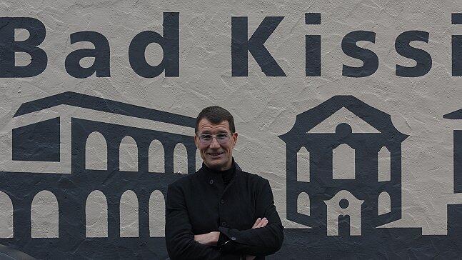 Kissinger Kulisse vom Arkadenbau über Kurtheater und Gradierbau bis zur Spielbank an der hinteren Zufahrt zum Salinenparkplatz: Malte Meinck vor einem Teil seines Werks. Kissinger Kulisse vom Arkadenbau über Kurtheater und Gradierbau bis zur Spielbank an der hinteren Zufahrt zum Salinenparkplatz: Malte Meinck vor einem Teil seines Werks.