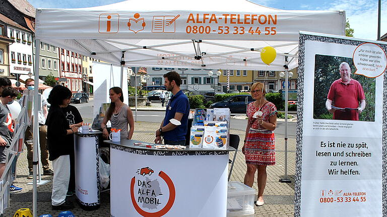 Informationsstände auf dem Marktplatz greifen die Probleme der Menschen mit Lese- und Schreibschwierigkeiten auf, hier der Stand des Alfa-Mobils mit Susann Günther und Adrian Eppel sowie&nbsp; Renate Knaut (rechts) von der vhs Rhön und Grabfeld.