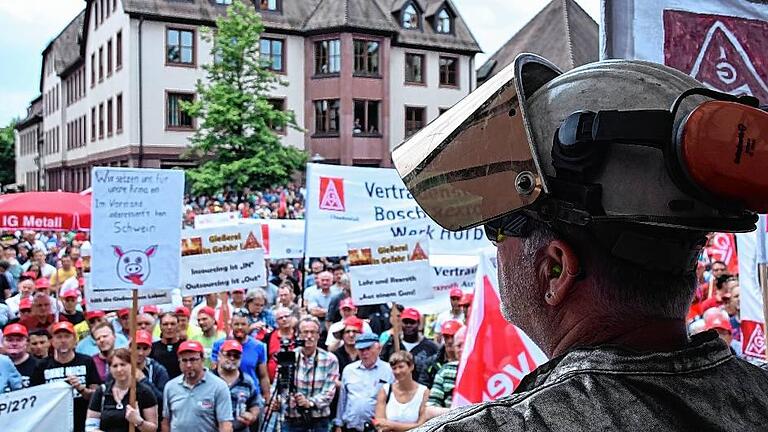 Vollbesetzter Schlossplatz: Ein Mitarbeiter der Rexroth-Gießerei blickt in voller Arbeitsmontur auf die von Rexroth-Standorten aus ganz Deutschland angereisten Demonstranten. Vollbesetzter Schlossplatz: Ein Mitarbeiter der Rexroth-Gießerei blickt in voller Arbeitsmontur auf die von Rexroth-Standorten aus ganz Deutschland angereisten Demonstranten.
