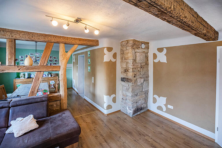 Das Wohnzimmer von Familie Werner, der Zugang zum hinteren Essbereich war zuvor von einer Wand getrennt, die herausgerissen wurde. Die Hauswand (rechts) ist aus Lehm, der alte Kamin aus Sandstein wurde restauriert. Ein Holzstamm (Mitte) gilt als Gestaltungsmittel. Das Wohnzimmer von Familie Werner, der Zugang zum hinteren Essbereich war zuvor von einer Wand getrennt, die herausgerissen wurde. Die Hauswand (rechts) ist aus Lehm, der alte Kamin aus Sandstein wurde restauriert. Ein Holzstamm (Mitte) gilt als Gestaltungsmittel.