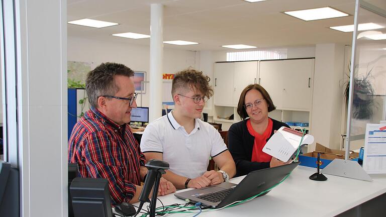 Der 17-jährige Fabian Gröber (Mitte) absolviert bei den Hammelburger Stadtwerken eine Ausbildung zum IT-System-Kaufmann. Hier schauen ihm Betriebsleiter Stephan Dausacker (links) und Geschäftsführerin Anja Binder (rechts) beim Konfigurieren eines Routers über die Schulter. Foto: Ralf Ruppert - Der 17-jährige Fabian Gröber (Mitte) absolviert bei den Hammelburger Stadtwerken eine Ausbildung zum IT-System-Kaufmann. Hier schauen ihm Betriebsleiter Stephan Dausacker (links) und Geschäftsführerin Anja Binder (rechts) beim Konfigurieren eines Routers über die Schulter. Foto: Ralf Ruppert Der 17-jährige Fabian Gröber (Mitte) absolviert bei den Hammelburger Stadtwerken eine Ausbildung zum IT-System-Kaufmann. Hier schauen ihm Betriebsleiter Stephan Dausacker (links) und Geschäftsführerin Anja Binder (rechts) beim Konfigurieren eines Routers über die Schulter. Foto: Ralf Ruppert - Der 17-jährige Fabian Gröber (Mitte) absolviert bei den Hammelburger Stadtwerken eine Ausbildung zum IT-System-Kaufmann. Hier schauen ihm Betriebsleiter Stephan Dausacker (links) und Geschäftsführerin Anja Binder (rechts) beim Konfigurieren eines Routers über die Schulter. Foto: Ralf Ruppert
