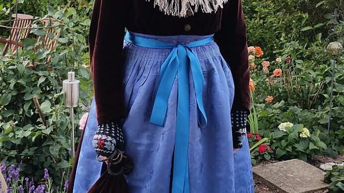 Das Samtblusenkleid ersetzte die Festtracht mit dem Körres. Hier wurde das eigentliche Winter-Kopftuch („Hinterbindhulla“) als Schultertuch wie bei der alten Tracht getragen. Auffällig ist auch die uni-farbene Seidenschürze mit eingewebtem Blumenmuster. Das Samtblusenkleid ersetzte die Festtracht mit dem Körres. Hier wurde das eigentliche Winter-Kopftuch („Hinterbindhulla“) als Schultertuch wie bei der alten Tracht getragen. Auffällig ist auch die uni-farbene Seidenschürze mit eingewebtem Blumenmuster.
