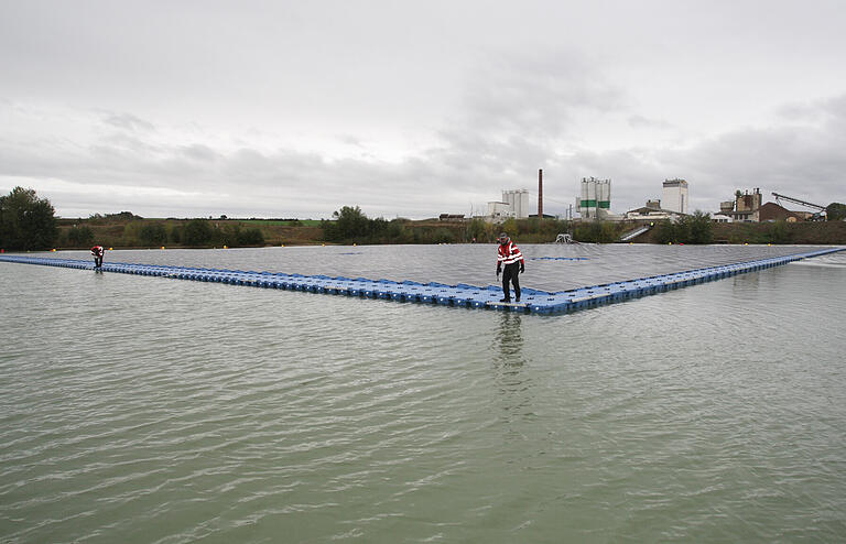 Noch wird am ersten freischwimmenden Solarkraftwerk Bayerns montiert, bis Ende des Jahres soll es in Betrieb gehen und das Sand- und Kieswerk im Hintergrund mit Strom versorgen.