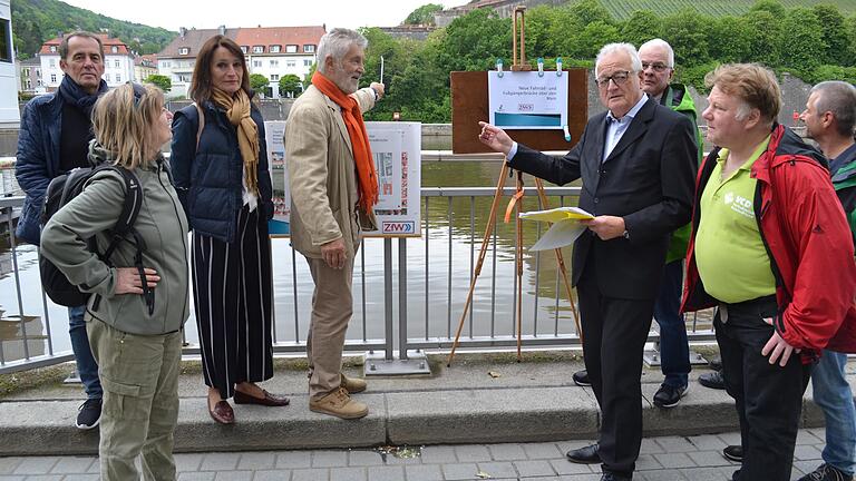 Michael Kraus (Vierter von links) und Wolfgang Baumann (Vierter von rechts) von der ZfW zeigen, wo eine Rad- und Fußgängerbrücke über den Main führen könnte.