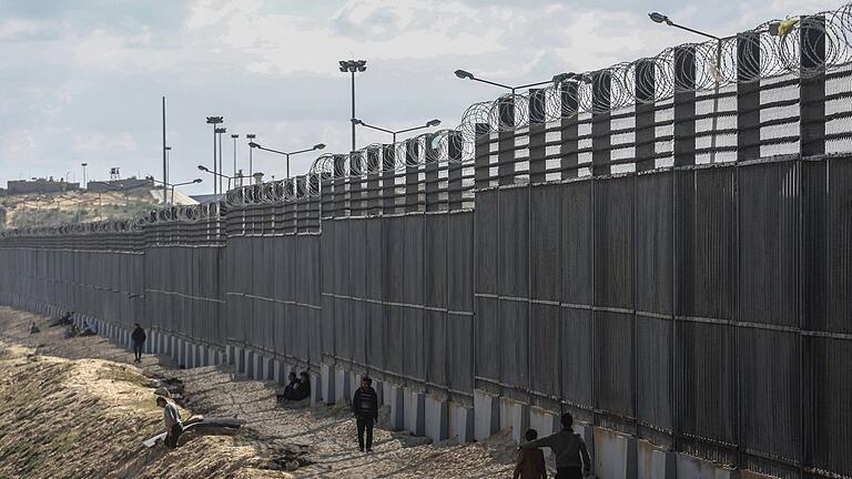 Grenze zwischen dem Gazastreifen und Ägypten.jpeg       -  Palästinenser stehen nahe der Grenze zwischen dem Gazastreifen und Ägypten (Archivbild).