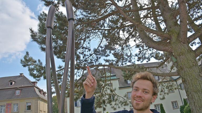 Paul Diestel erläutert sein Objekt im Park am Rindhof in Maria Bildhausen, dessen Ursprung eine Kiefernadel ist.