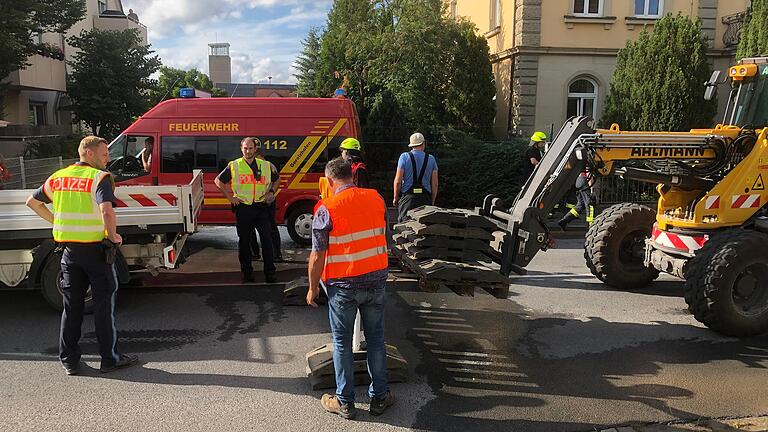 Feuerwehr und Bauhof bauen nach dem massiven Wasserrohrbruch in der Bahnhofstraße Absperrungen auf, um den Verkehr auf der stark befahrenen Staatsstraße umzuleiten.