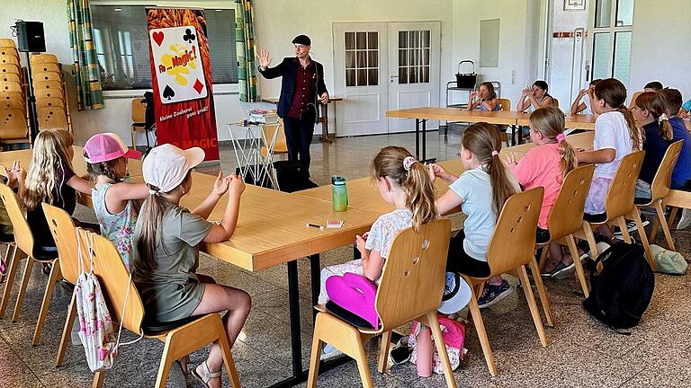 Die Kinder hören dem Zauberkünstler Mr. Flo aufmerksam und gespannt zu.