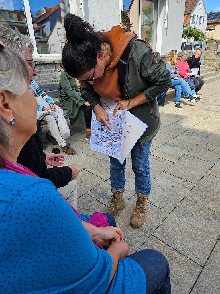 Monia Zecca vom Umweltbeirat zeigt anhand einer Planskizze, wie stark der Marktplatz mit Rohrleitungen unterbaut ist, was eine zusätzliche Bepflanzung schwierig macht.