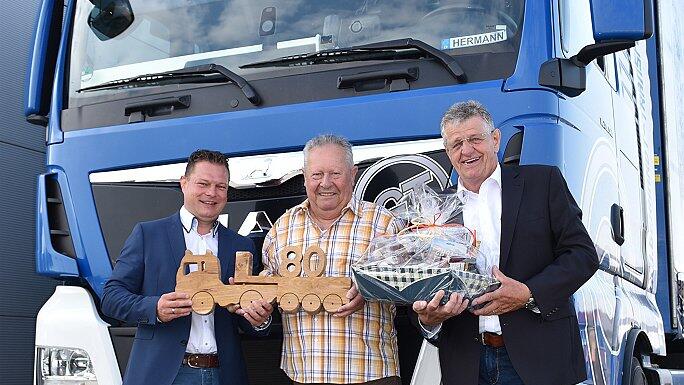 Gratulation vor dem &bdquo;rollenden Wohnzimmer mit Schlafgelegenheit&rdquo;. Christian Gerhardt (links) und Karl Gerhardt gratulierten Hermann Schneider nicht nur zum 80. Geburtstag, sondern vor allem zum außergewöhnlichen Jubiläum &bdquo;60 Jahre Lkw-Fahrer&rdquo;.