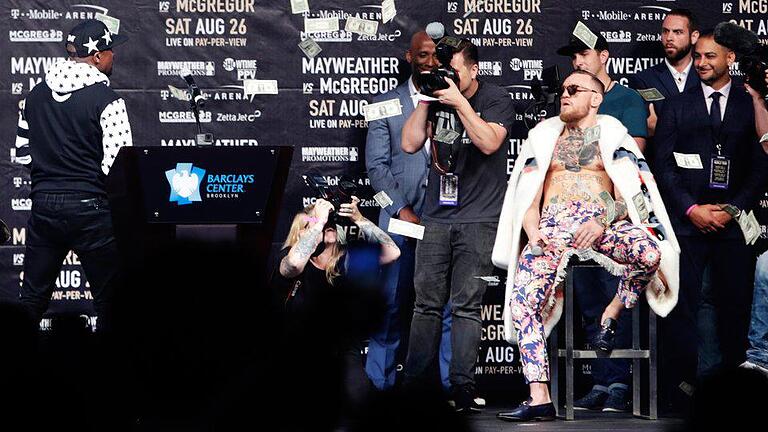 Geldregen       -  Floyd Mayweather Jr. (l) bewirft seinen Kontrahenten Conor McGregor mit Dollarnoten.