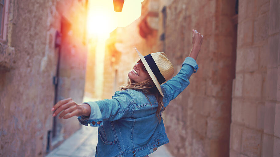 Happy woman walking on mediterreanen street in sunset - Schalten Sie ab: Gerade im Urlaub sollten Sie Ihr Smartphone auch einmal im Hotel lassen. Happy woman walking on mediterreanen street in sunset - Schalten Sie ab: Gerade im Urlaub sollten Sie Ihr Smartphone auch einmal im Hotel lassen.