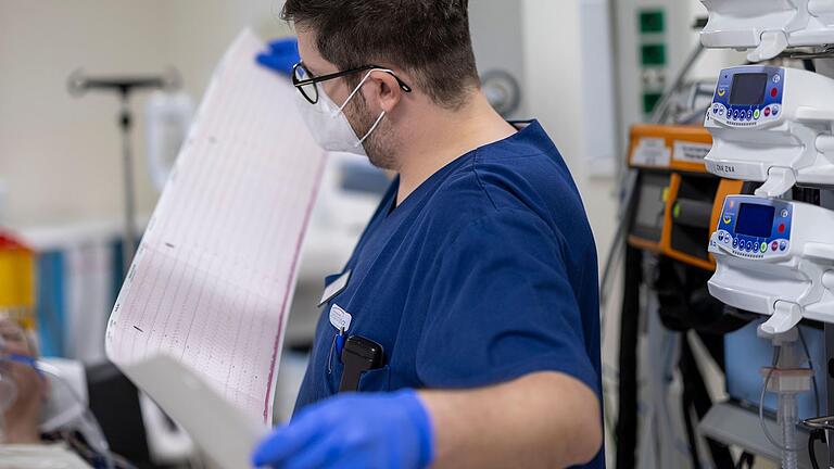 Chefarzt Dr. Benedikt Stubner schaut sich das EKG eines Patienten im Schockraum an, bevor er die weitere Behandlung durchführt.