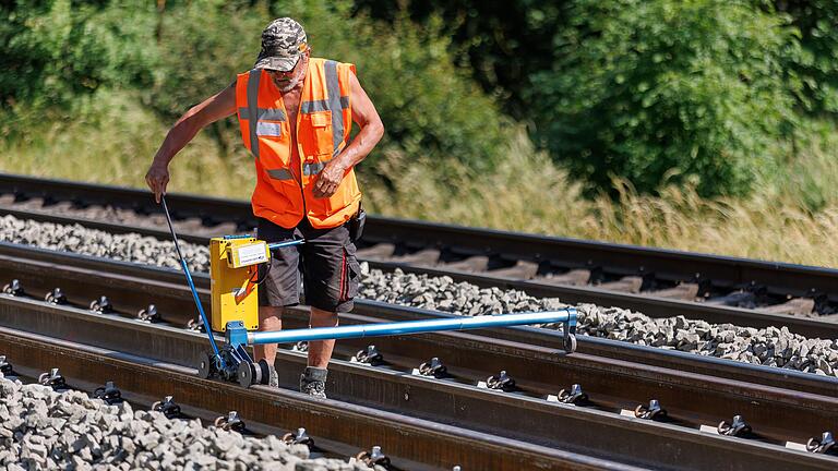 Ein Arbeiter überprüft auf einer Baustelle der Bahnstrecke Würzburg-Nürnberg die Gleislage der neu gelegten Schiene. Seit Wochen sind die Gleisarbeiter der Wärme und starken UV-Strahlung ausgesetzt.&nbsp;