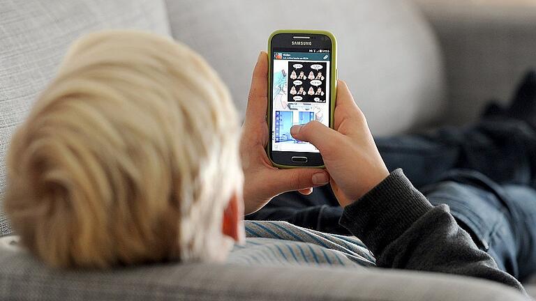 Jugendlicher mit Smartphone       -  Suchtprävention wird als Thema an der Heinrich-Thein-Berufsschule großgeschrieben. Dabei geht es nicht darum, Alkohol oder Soziale Medien zu verbieten, sondern &bdquo;zu wissen, wann man Nein sagen sollte &ndash; oder im anderen Fall zu wissen, wo man Hilfe bekommt&ldquo;, so Gesundheitsministerin Melanie Huml, die für die derzeit laufende Wanderausstellung &bdquo;Einfach Menschlich&ldquo; die Schirmherrschaft übernommen hat.