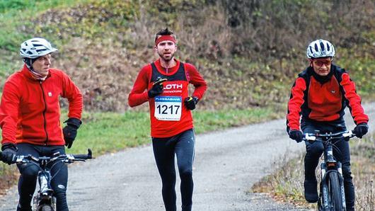 Weit und breit kein anderer Läufer in Sicht: mit 14 Minuten Vorsprung zum Zweiten lässt sich Adam Zahoran beim Marathon von den Begleit-Fahrradfahrern unterhalten.