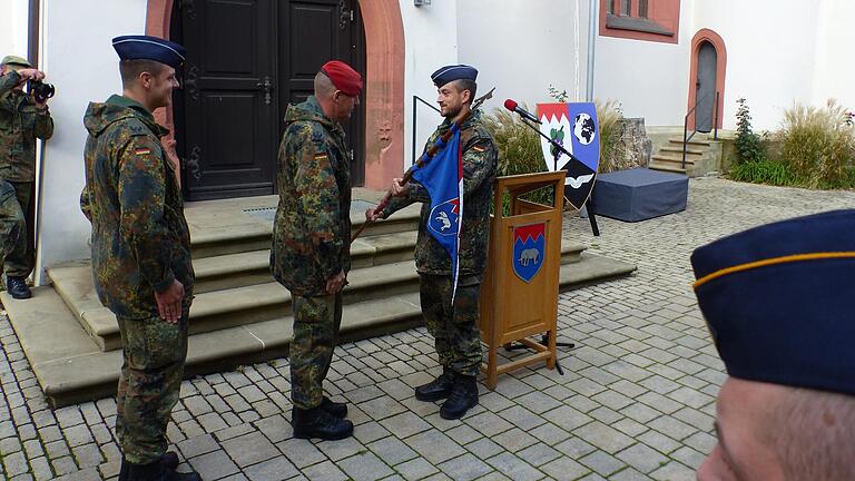 Oberstleutnant Holm Schreiter (Mitte) überreicht dem neuen Kompaniechef Hauptmann Alexander Kühn (rechts) den Kompaniewimpel. Links schaut der scheidende Major Sven Hartmann zu.