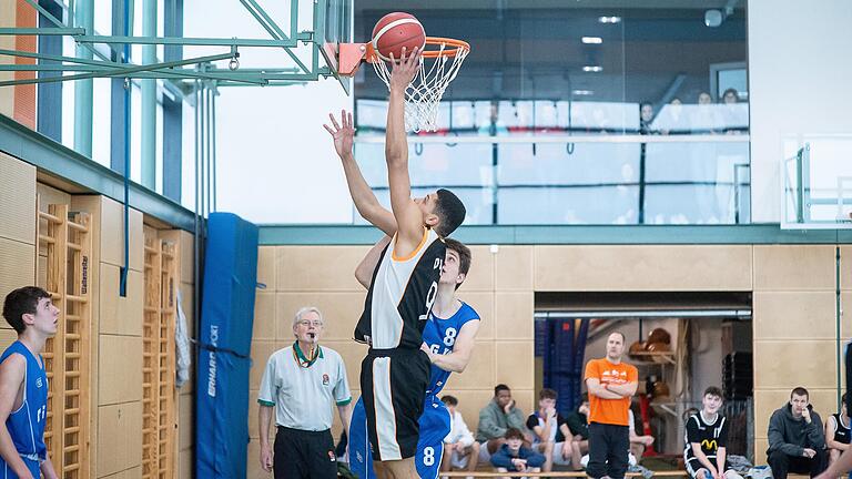 Bezirksentscheid Basketball: Tyrse Leonce von der Wilhelm-Sattler-Realschule bringt den Ball in den Korb. Sebastian Burek (Röntgen Gymnasium) kann ihn nicht mehr stoppen.