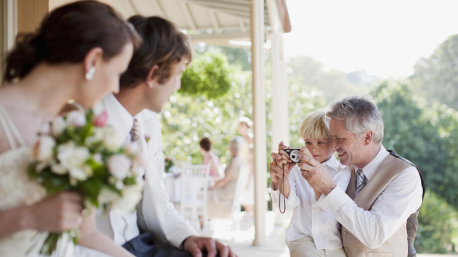 Father and son taking picture of bride and groom