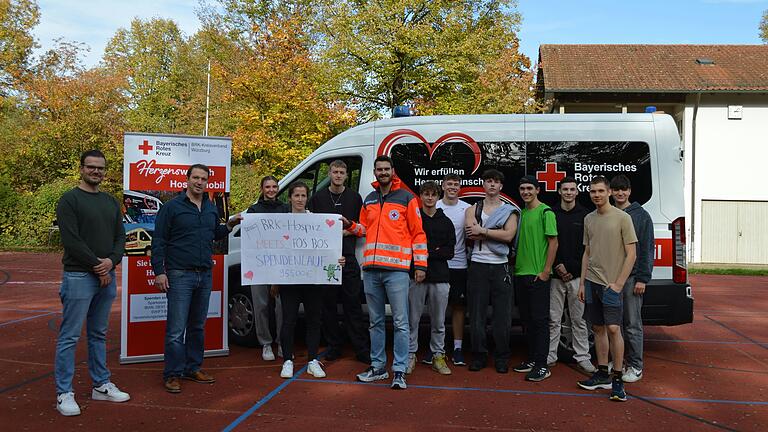 Das Foto zeigt Martin Steigert, Schulleiter i.V. Thomas Reinlein, Constanze Böck (4. v.l.), Fabian Wanninger (BRK Herzenswunsch Hospizmobil, 6. v.l.) und Schülerinnen und Schüler der FOSBOS Kitzingen.